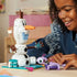 LEGO Disney Frozen Olaf and Bruni play experience showing a child smiling while posing the white snowman figure with twig arms, picnic mug, and purple Bruni in a cozy room.