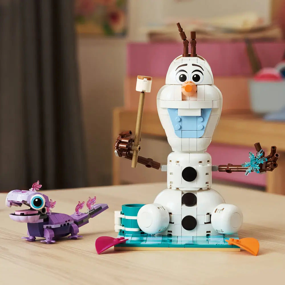 LEGO Disney Frozen Olaf and Bruni set fully built, featuring white snowman with carrot nose, blue chest tiles, twig arms, picnic accessories, and Bruni displayed on a tabletop.