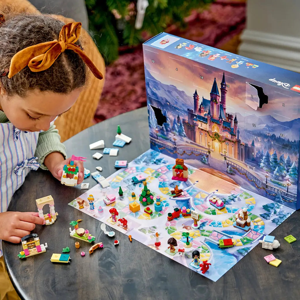 LEGO Disney Princess Advent Calendar 2026 play scene features colorful plastic figures, animals and holiday mini builds on a snowy game mat as a child builds a castle tower.