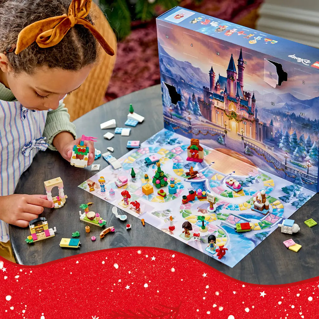 LEGO Disney Princess Advent Calendar 2026 play scene shows colorful plastic figures and festive mini builds across a snowy game mat as a child builds a decorated castle tower.