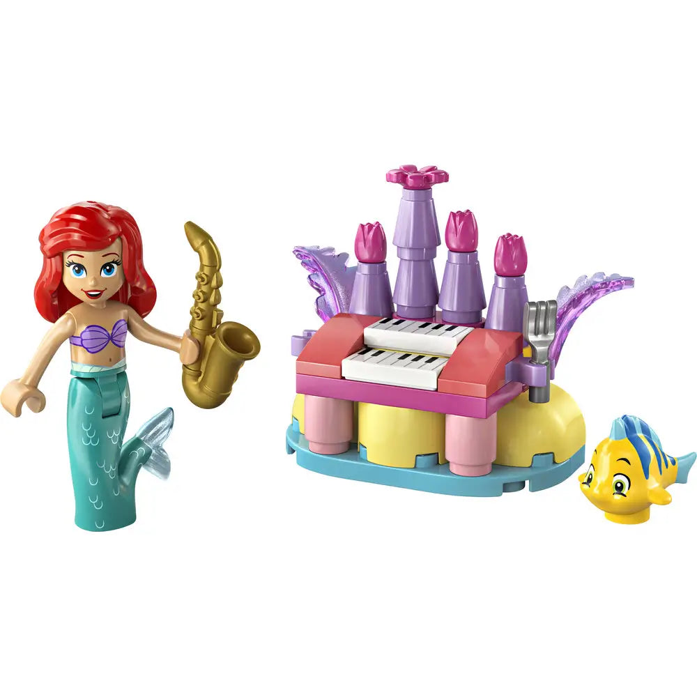 LEGO Disney Ariel birthday music playset built from pastel pink, purple, yellow, and blue plastic bricks, featuring a small organ-style music build, decorative sea shapes, Ariel mermaid mini doll holding a gold saxophone, and Flounder figure on a white studio background.