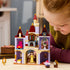 LEGO Disney Princess castle in lavender, tan, red, and gold plastic is explored by a child at a table, with Belle, Beast, Cogsworth, Lumiere, rose, and furnished rooms.