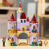 LEGO Disney Princess castle set in lavender, tan, red, and gold plastic shows Belle and Beast beside an arched castle with rose balcony, flowers, Lumiere, and Cogsworth.