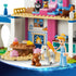 LEGO Disney Princess Cinderella Animal Friends Castle close-up in pink, blue, tan, and white plastic shows Cinderella grooming a horse beside a table, dog, and fireplace.