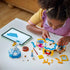 LEGO Disney Princess Cinderella dress set in blue, white and gold plastic with open wardrobe sections and build pieces as a child follows digital instructions on a tablet at a white table indoors.