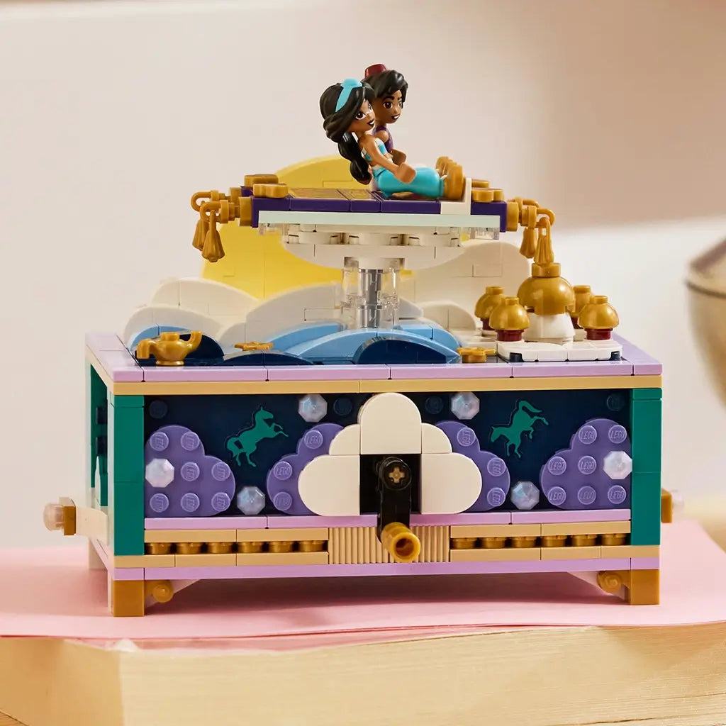 LEGO Disney Princess Jasmine's Jewelry Box in teal, lavender, white, and gold plastic is displayed on a pink book with Jasmine and Aladdin figures seated atop the palace scene.