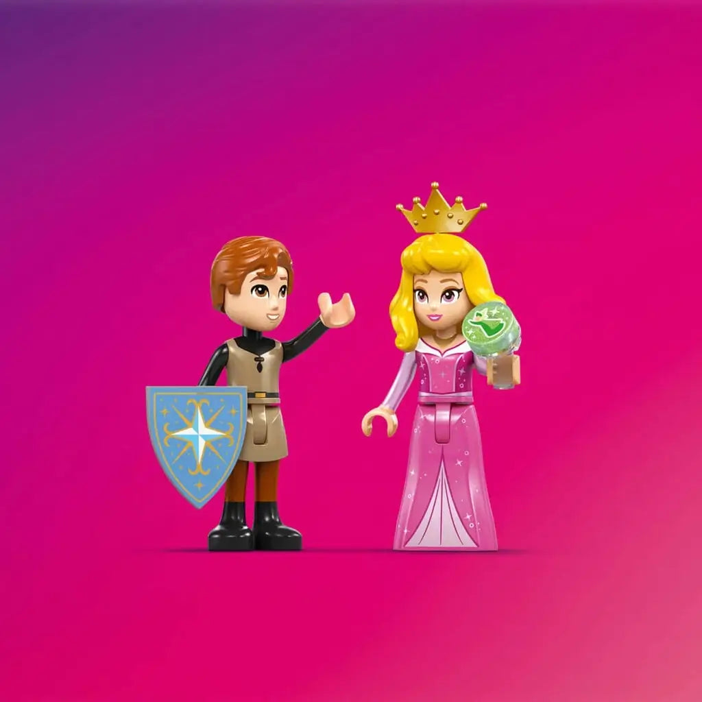 LEGO Disney Princess Aurora and Prince Phillip minifigures in pink, tan and black plastic with a shield and spinning wheel accessory, displayed against a bright pink background.