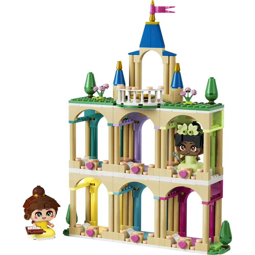 LEGO Disney Princess castle playset featuring tan and pastel plastic bricks, a tiered arched tower with blue spires, pink flag, heart accents, and balcony details, displayed on a white background.