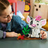 LEGO Disney Moana Pua building set in white, gray, pink, green, and brown plastic is explored by a child at a table, with Pua, Heihei, a leafy plant, and brown display base.