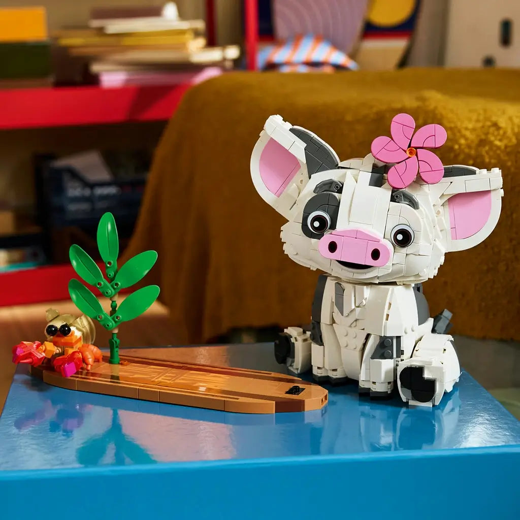 LEGO Disney Moana Pua set in white, gray, pink, green, brown, and orange plastic shows the seated pig with a pink flower beside a leafy plant and Heihei on a canoe-style base.