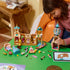 LEGO Disney Princess Rapunzel's Castle in tan, pink, turquoise, and gold plastic is opened into modular rooms as a child builds a tower beside loose pieces and a tablet.