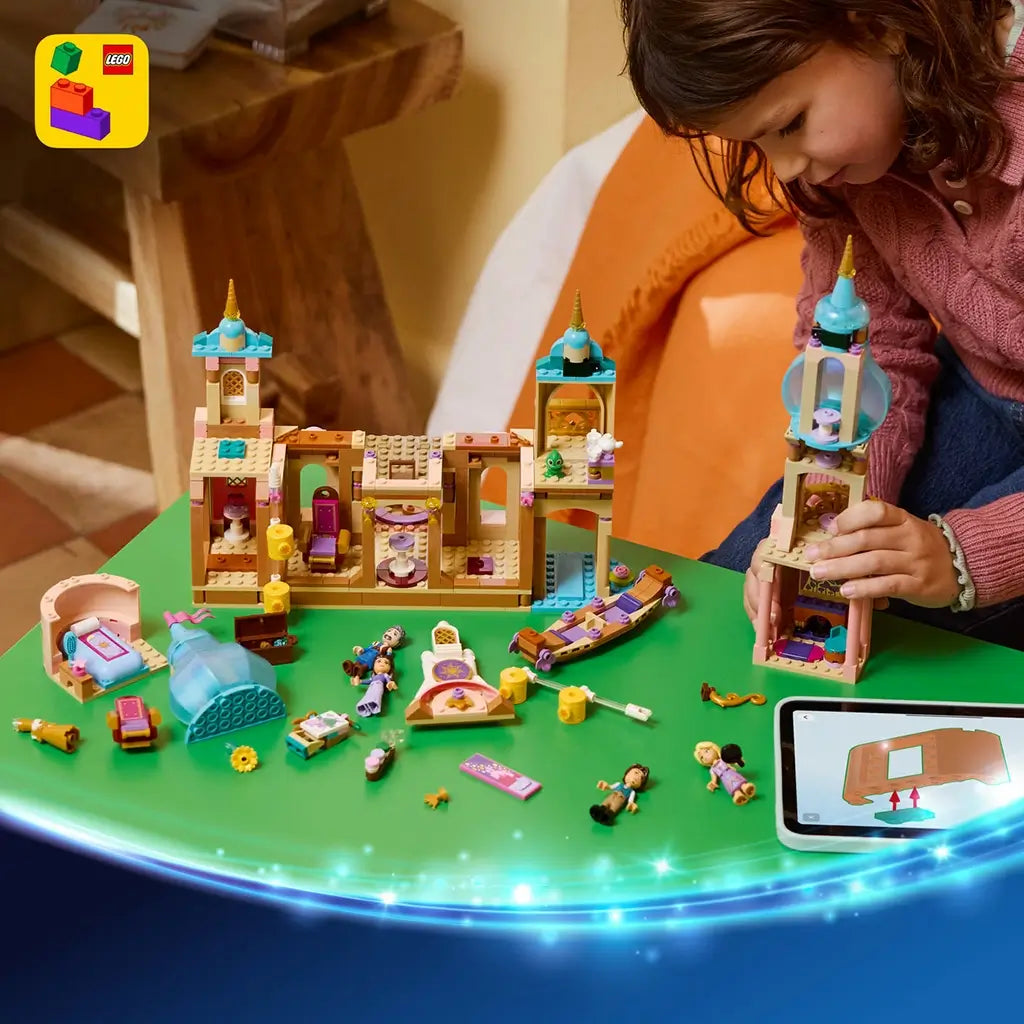 LEGO Disney Princess Rapunzel's Castle pieces in tan, pink, turquoise, and gold plastic cover a green table as a child builds a tower beside digital instructions on a tablet.