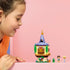LEGO Disney Princess Rapunzel's Mini Tower in yellow, tan, purple, green, and gold plastic is displayed as one closed round tower beside Rapunzel, Flynn Rider, and Pascal figures.