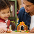 LEGO Disney Moana Village House & Boat in tan, orange, green, and pink plastic is displayed as an adult and child play with the tropical house, canoe, figures, and pig.