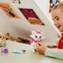 LEGO Disney Aristocats Marie play experience showing a child smiling while posing the white cat figure with pink bow, collar, and small accessory pieces in a bright indoor room.