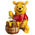 LEGO Disney Winnie the Pooh figure in bright yellow and red plastic, rounded character holding honey pot with dripping detail and bees, collectible display model on a clean white background.