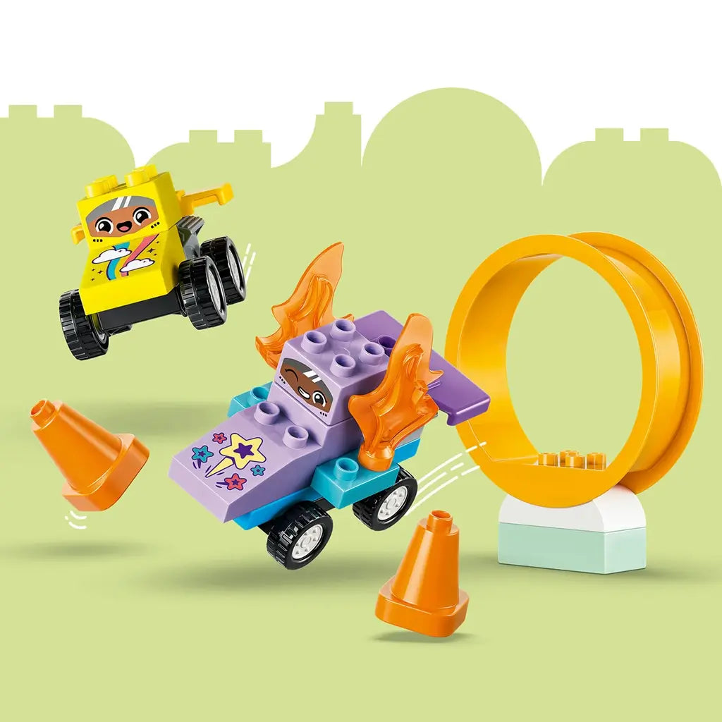 LEGO DUPLO race cars feature yellow and purple plastic bodies with black wheels, jumping through an orange loop and around matching cones on a pale green background.