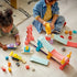 LEGO DUPLO Creative Ramps playset features pastel plastic ramps, towers and an orange loop as two children build and race colorful cars together on a wooden floor.