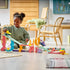 LEGO DUPLO ramp playset features pastel plastic towers, slopes and an orange loop as a child races yellow and purple cars across a bright living room floor.