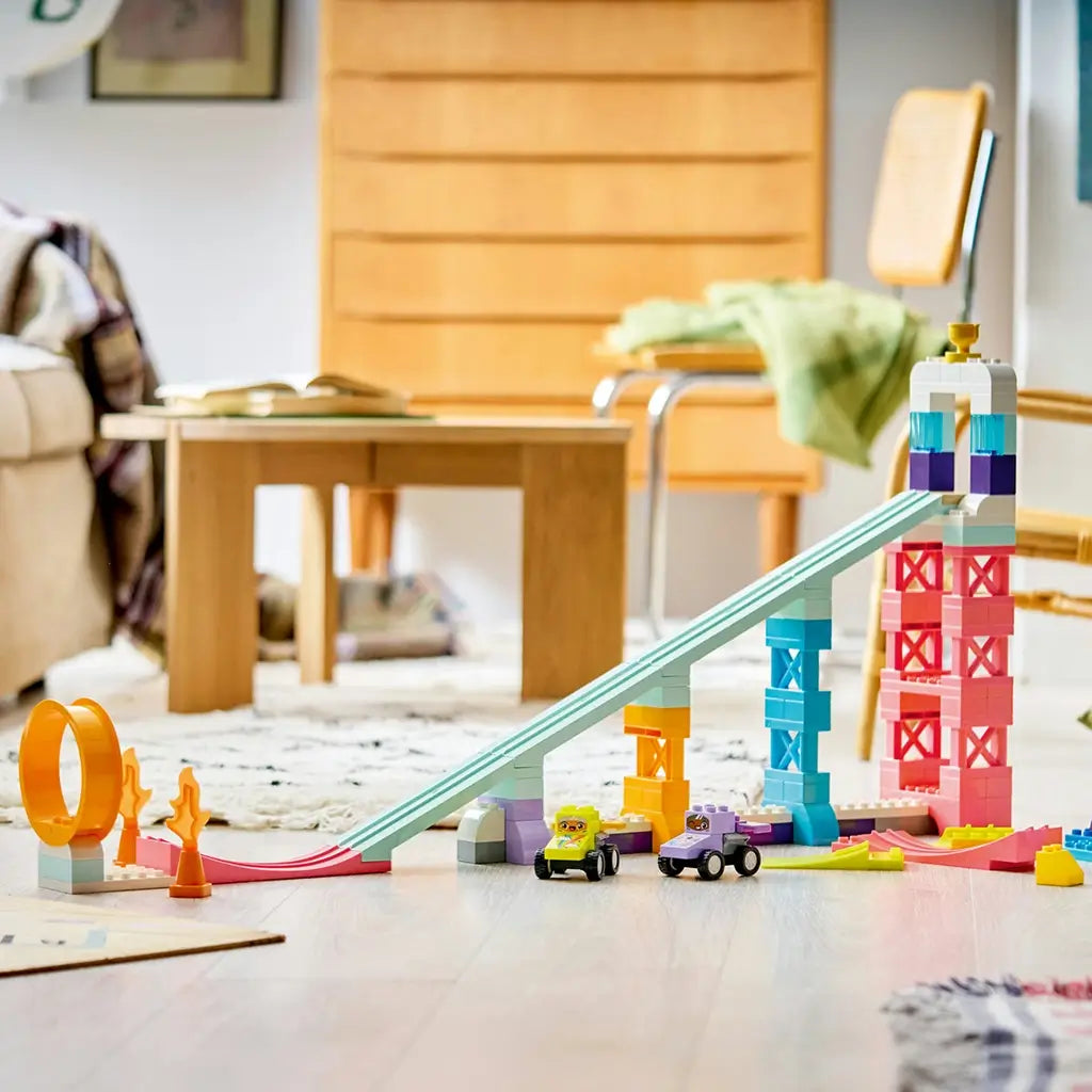 LEGO DUPLO Creative Ramps display features mint, pink, blue and white plastic towers, a long sloped track, orange loop, two race cars and loose ramps in a living room.