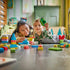 LEGO DUPLO Colorful Creative Box playset shows a child holding a green plastic propeller build beside an adult, with colorful ducks, boats, flowers and bricks on the floor.