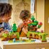 LEGO DUPLO Discovery Forest playset features green and brown plastic forest habitats as a child uses a red magnifier beside an adult, with animal figures arranged on a table.