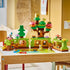 LEGO DUPLO Discovery Forest playset displays green and brown forest habitats, pink and purple flowers, five wild animal figures, red and blue magnifiers on a wooden table.