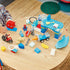 LEGO DUPLO Marvel Spidey Webquarters play scene shows blue and white plastic headquarters pieces, Spidey figures, vehicles and accessories spread across a wooden table.