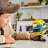 LEGO Ayrton Senna Helmet set 43024 displays a yellow, green and blue brick-built racing helmet on a black stand with plaque and minifigure as a young builder looks on.
