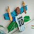 LEGO Lionel Messi collectible wall art features white, sky-blue and green plastic brick construction shaped as the number 10 Argentina jersey celebration display, mounted above a shelf in a modern room.