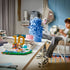 LEGO Lionel Messi soccer display in blue, green, white and gold plastic bricks, arranged as a number 10 highlight scene with goal frame and football effect, showcased on a desk in a home setting.