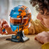 LEGO McLaren Formula 1 helmet collectible features blue, orange and black plastic brick construction styled after Oscar Piastri’s racing helmet, displayed on a stand while a builder holds the minifigure.