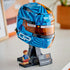 LEGO McLaren Formula 1 helmet display features blue, orange and black plastic brick construction shaped as Oscar Piastri’s racing helmet with reflective visor, mounted on a stand beside a minifigure.