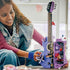 LEGO Olivia Rodrigo Dual Guitar in lavender and black bricks opens to reveal a detailed interior as a young builder handles the butterfly feature in a bright room.