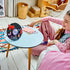 LEGO Olivia Rodrigo Vinyl display in black, purple and red bricks stands on a blue table as a smiling builder views the finished record, butterflies and minifigure.