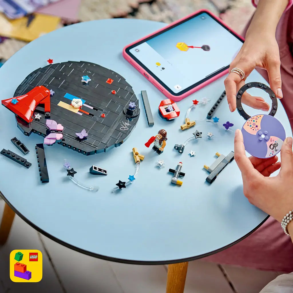 LEGO Olivia Rodrigo Vinyl set in black, purple and red bricks is assembled on a blue table, with loose stars, butterflies, a minifigure and digital instructions nearby.