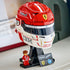 LEGO Ferrari Charles Leclerc helmet collectible features red, white and black glossy plastic brick construction shaped as a Formula 1 racing helmet on a display stand, showcased on a shelf beside the included minifigure.