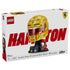 LEGO Ferrari Formula 1 helmet collectible features metallic yellow and red plastic panels forming Lewis Hamilton’s racing helmet, displayed with a branded stand and Ferrari minifigure on premium retail packaging.