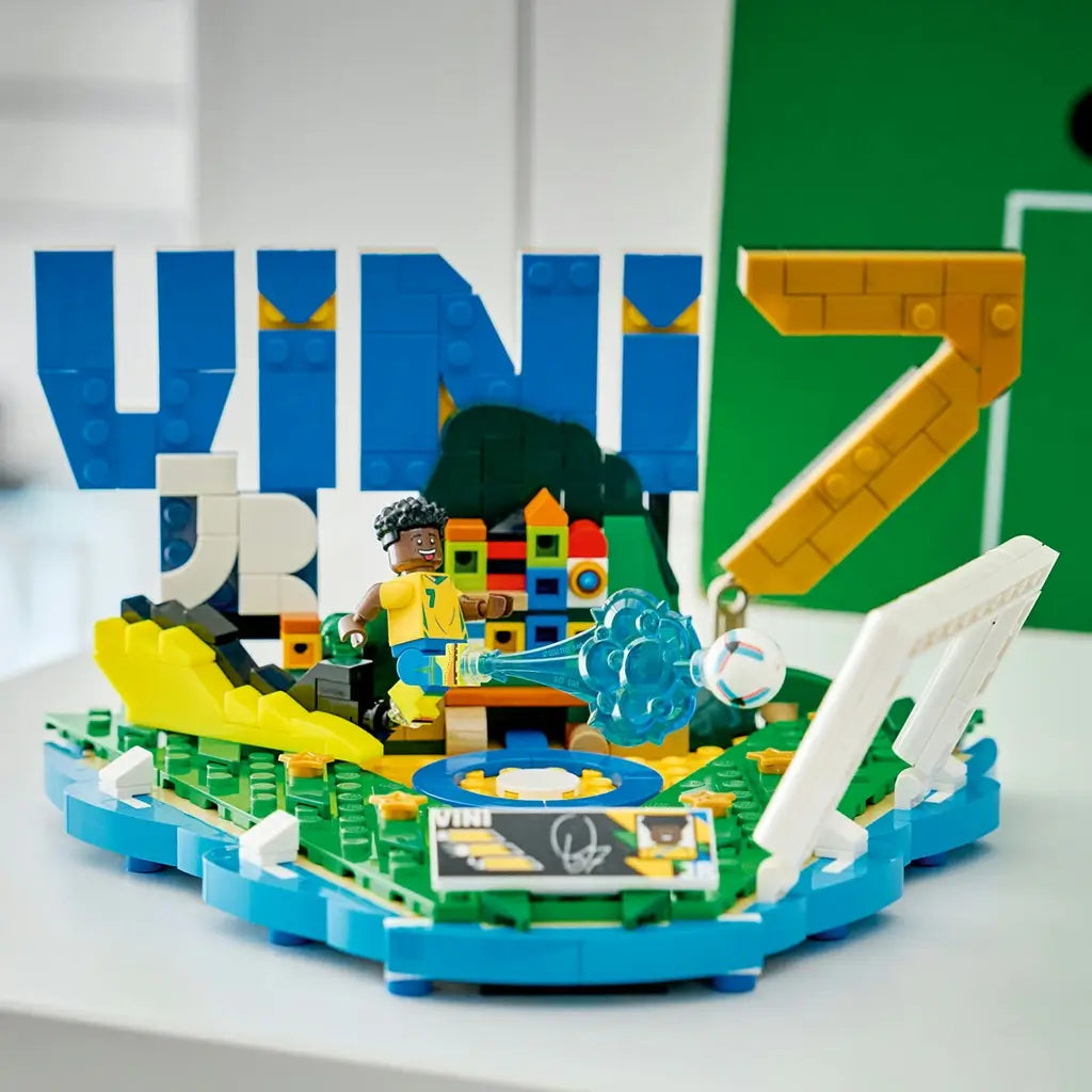 LEGO Editions Vini Jr. Soccer Highlights showcases blue, yellow, green and white plastic lettering, football goal details and a player minifigure arranged as a display piece on a shelf with a sports-themed backdrop.