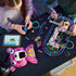 LEGO Fortnite Rave Cave in pink, white and purple plastic bricks is assembled by two builders at a black table, with rail sections, minifigures and digital instructions nearby.