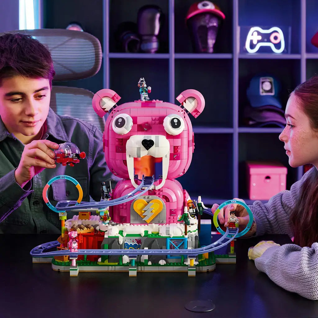 LEGO Fortnite Rave Cave in pink, white and purple plastic bricks is used for play by two builders, with a bear-shaped venue, looping rail track, vehicle and minifigures.