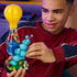 LEGO Fortnite Supply Drop set in yellow, blue and turquoise plastic bricks is held by a builder, featuring a balloon crate, bubble effect, green base and three figures.