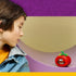 LEGO Fortnite Tomatohead set in red, green and brown plastic bricks sits on a curved purple shelf as a child looks toward the smiling tomato display in a colorful room.