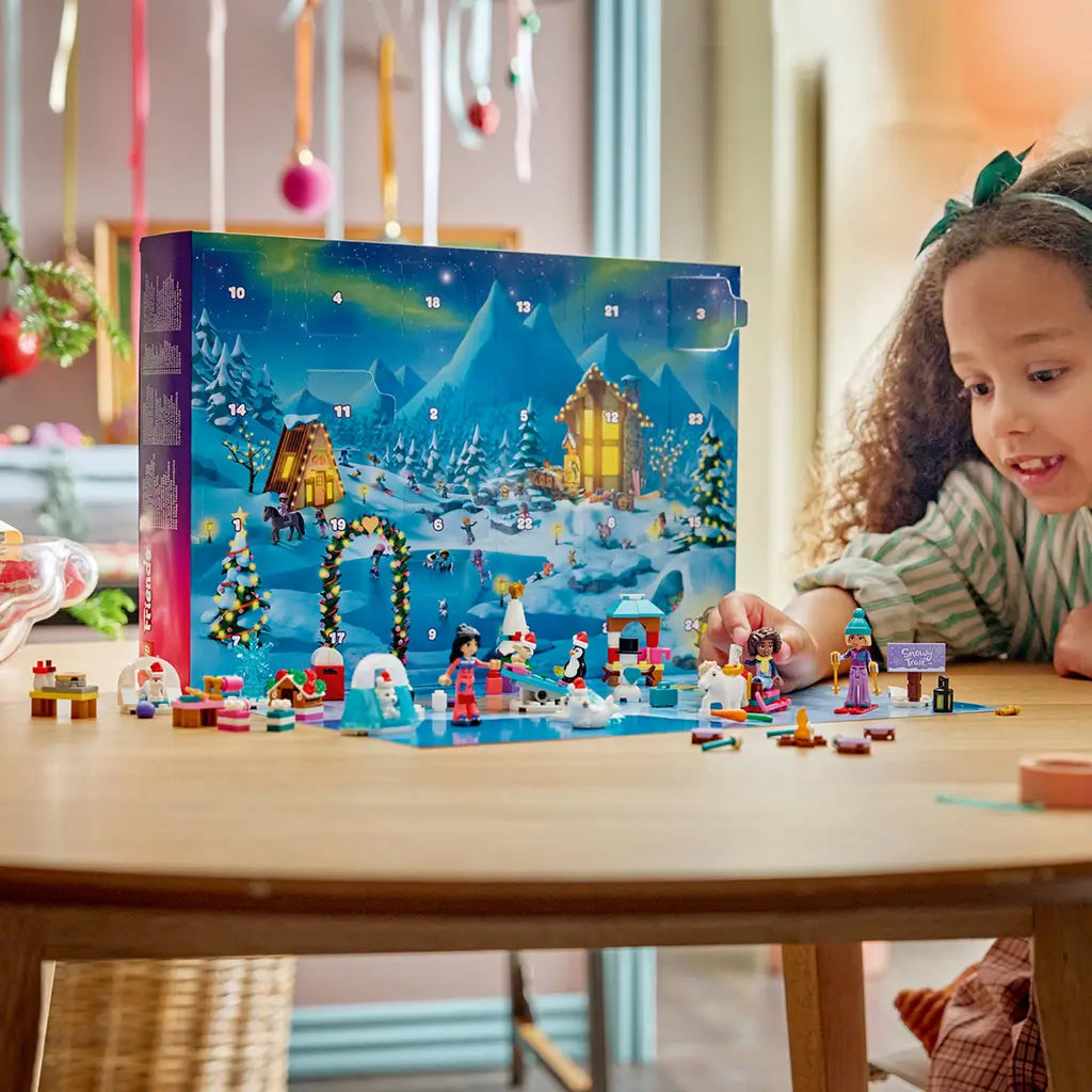 LEGO Friends Advent Calendar 2026 features colorful plastic mini-dolls, animals and winter builds arranged before a snowy 24-door calendar as a child plays at a table.