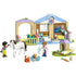 LEGO Friends animal vet clinic playset built in tan, light blue, and pastel plastic bricks, single-story clinic with archway, exam room, fenced yard, and small animals, designed for caring role-play on a clean white background.