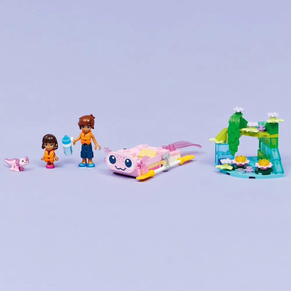 LEGO Friends axolotl adventure display showing pastel pink, teal, and green plastic bricks forming a finished boat and pond habitat with flowers, animals, accessories, and minifigures posed on a tabletop.