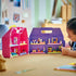 LEGO Friends dollhouse suitcase in pink and purple plastic opens into four furnished rooms while a child plays with a mini-doll and plant pieces at a home table.