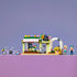 LEGO Friends Creative Flower Shop in green, pink and white plastic, with colorful blooms, tandem bicycle and two mini-dolls displayed on a purple tabletop.
