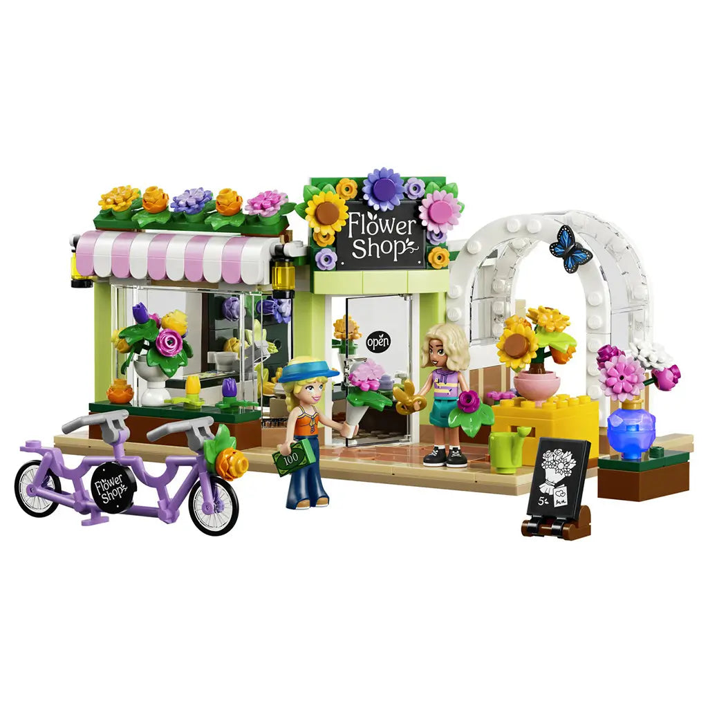 LEGO Friends Creative Flower Shop 42693 in green, pink and white plastic, with two mini-dolls, tandem bicycle, flower displays and shop sign on a white background.