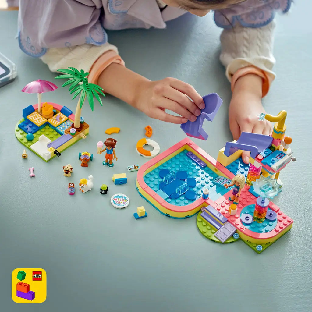 LEGO Friends Fun Water Park Day build in pink, aqua and purple plastic, with a child assembling the slide beside a pool, mini-dolls, pet figures and loose pieces.